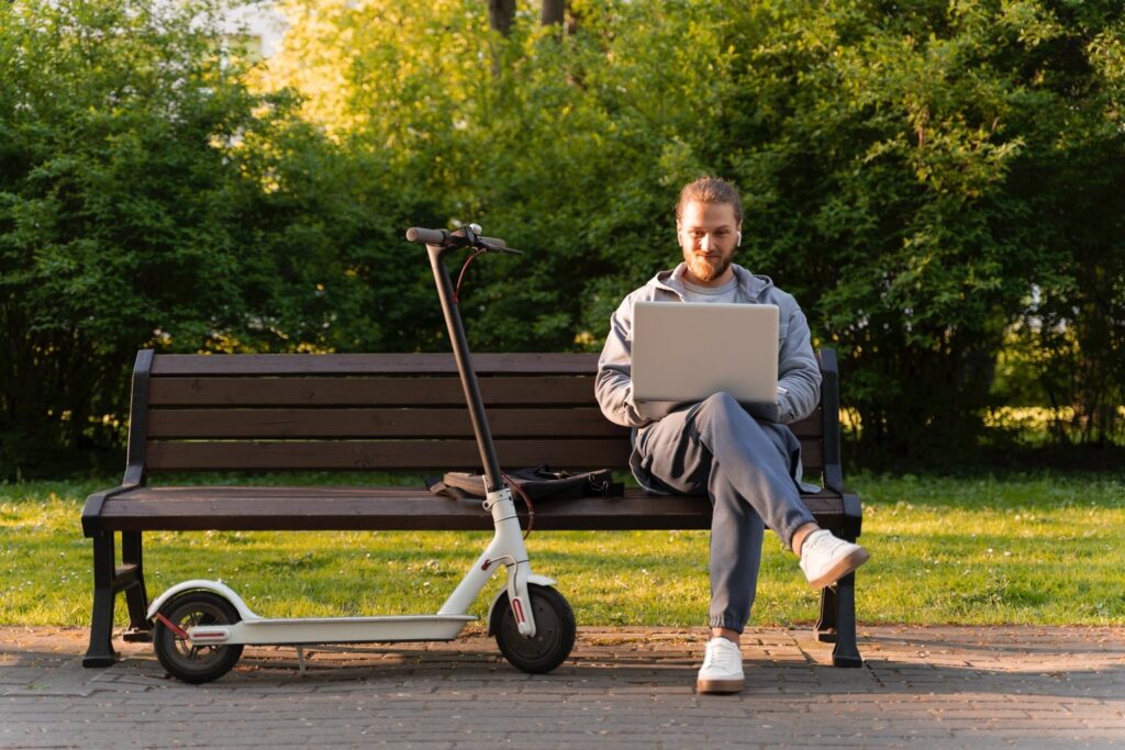 Man using laptop beside scooter – LSSC scam awareness article