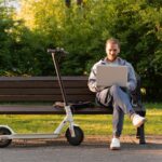 Man using laptop beside scooter – LSSC scam awareness article